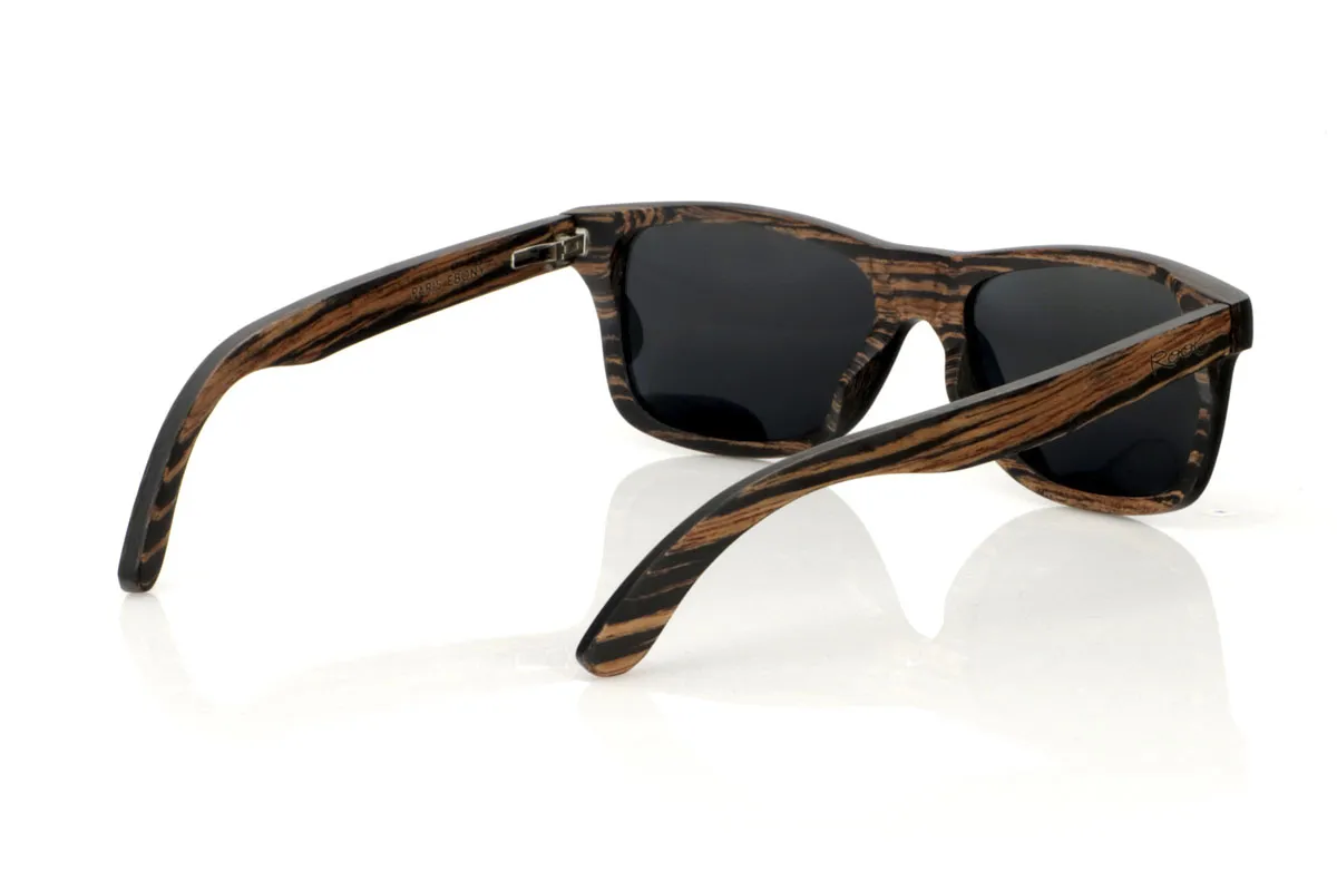 Wood eyewear of Ebony PARIS. PARIS wooden sunglasses feature a classic silhouette with a more square touch and a medium size, ideal for those looking for a timeless style with a perfect fit. This model is entirely made of African ebony wood, with an impressive grain in black and brown tones, which provides an air of sophistication. With measurements of 148x45 and a caliber of 54, the PARIS are perfect for those who value durability and design in their accessories. This pair is not only a complement to your outfit, but a statement of style and appreciation for natural details and quality craftsmanship. for Wholesale & Retail | Root Sunglasses® 